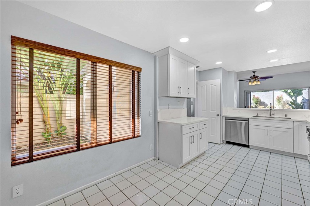Bright Kitchen with White Cabinets and Large Window Overlooking Patio Area