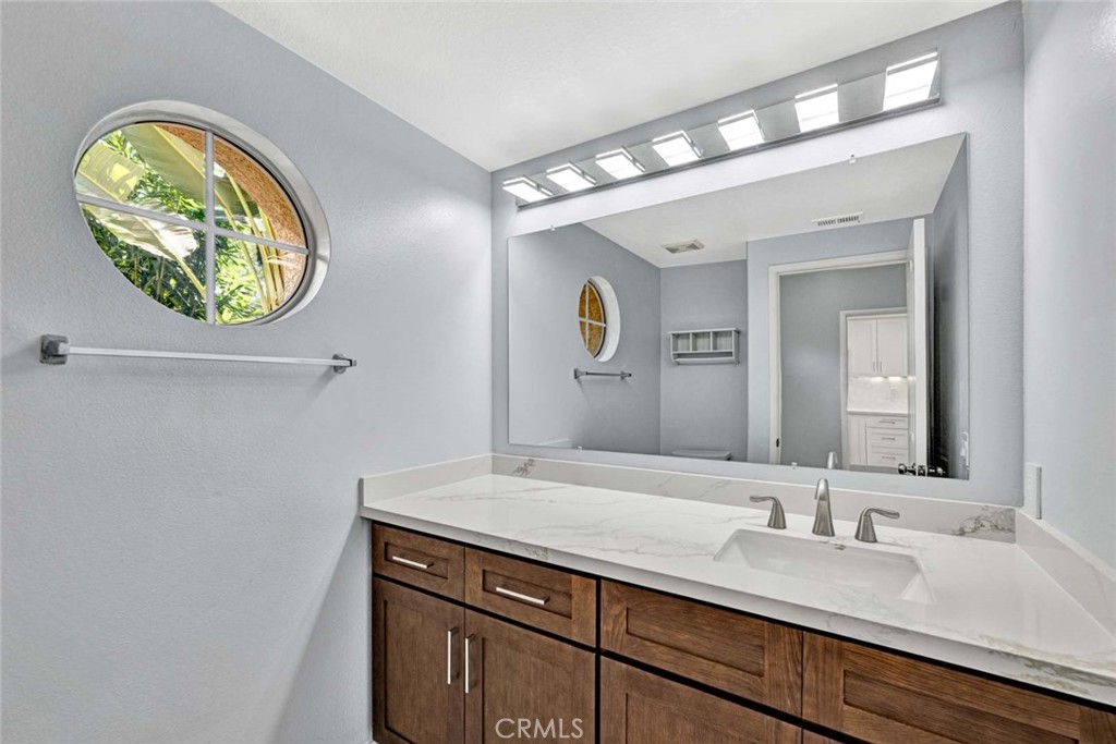 Modern Bathroom with Large Mirror and Wooden Vanity in Real Estate Listing