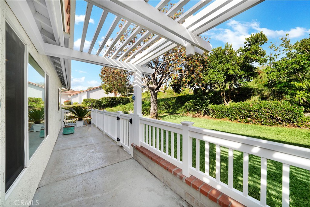 White Pergola and Fenced Patio Overlooking Green Backyard in Real Estate Listings