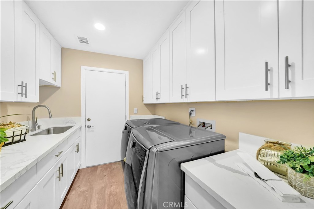 Modern Laundry Room with White Cabinets and Stainless Steel Appliances