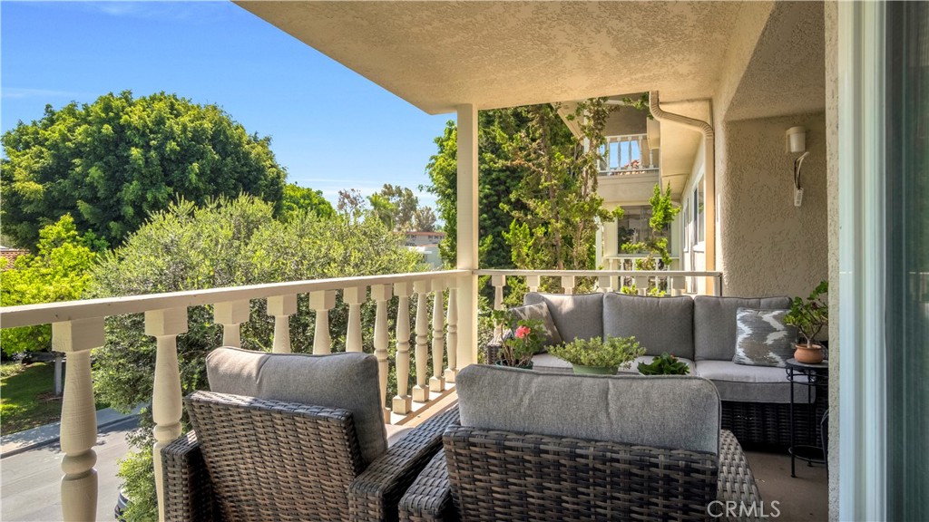Cozy Balcony with Wicker Furniture Overlooking Lush Trees and Real Estate Listings