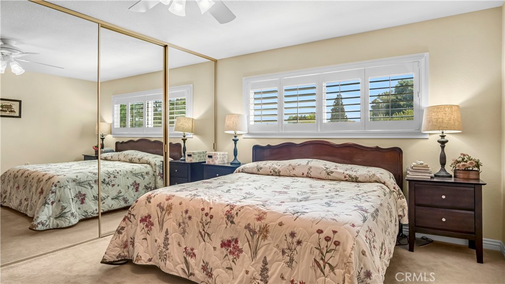Bedroom with Floral Bedding and Large Mirror in Real Estate Listing