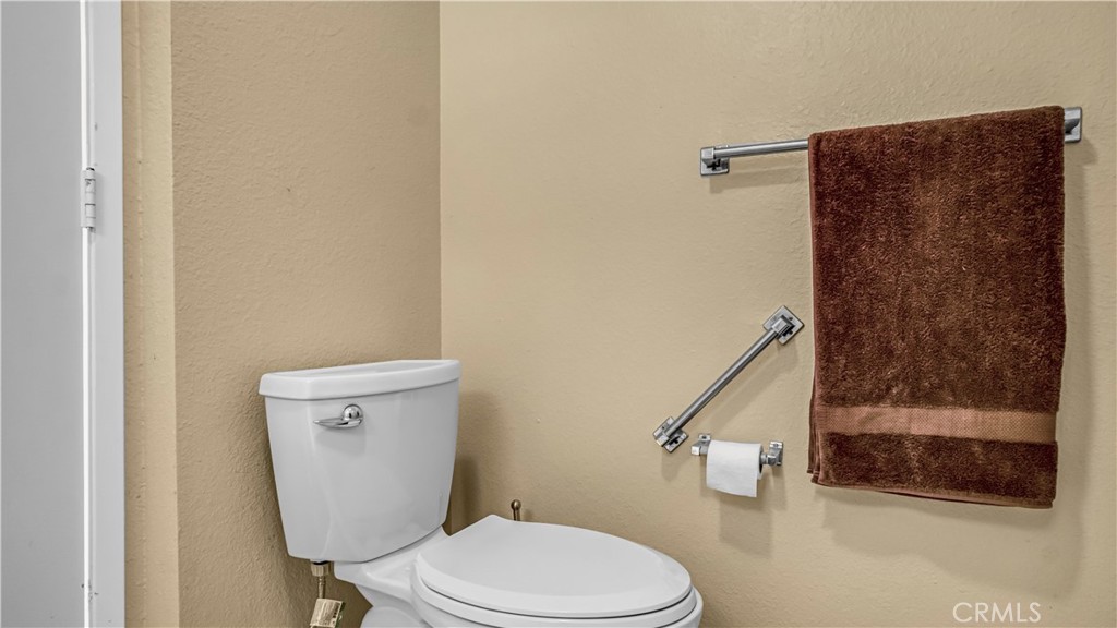 Bathroom with Beige Walls, White Toilet, and Brown Towel on Rack