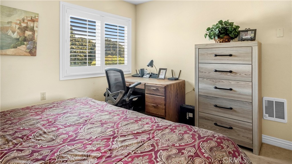 Bedroom with Wooden Desk, Chair, and Dresser by a Window