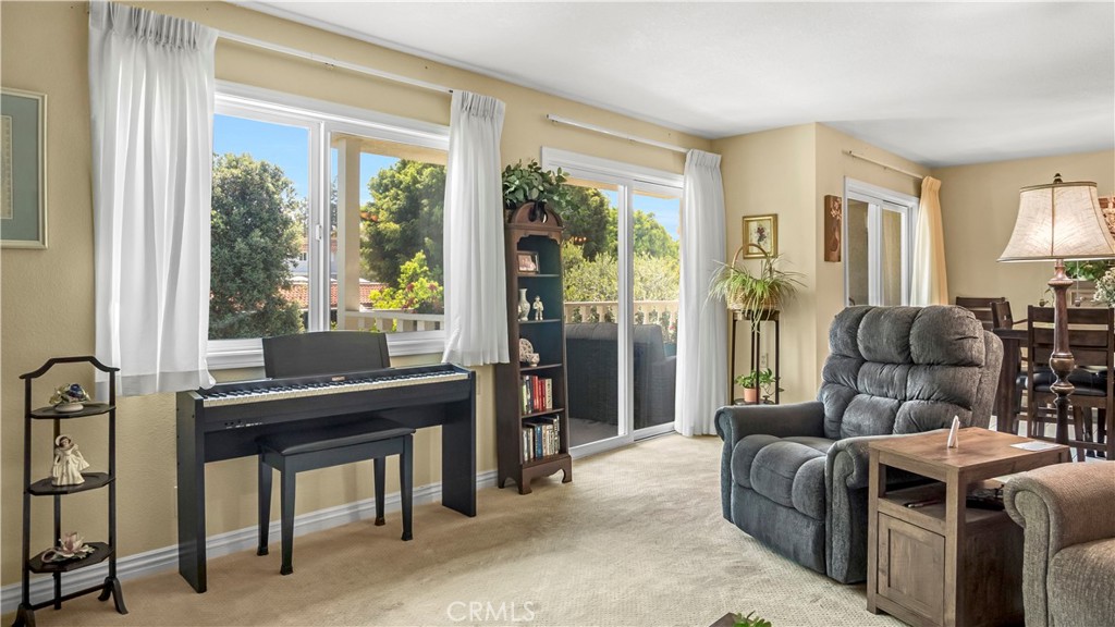 Bright Living Room With Piano, Armchair, Balcony View, and Real Estate Listings