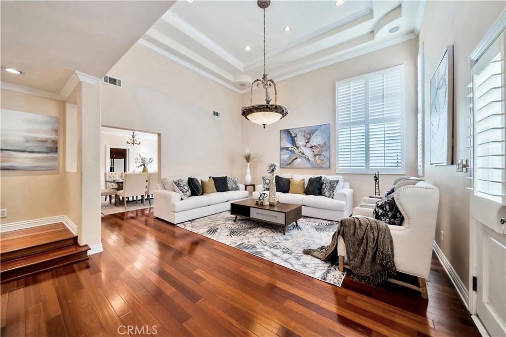 Living room with vaulted ceiling, hardwood floors, and neutral decor