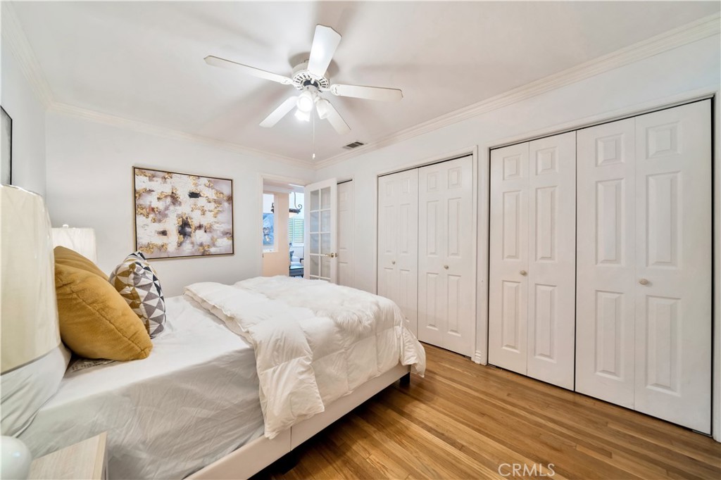 Bedroom with white furniture, ceiling fan, and hardwood flooring