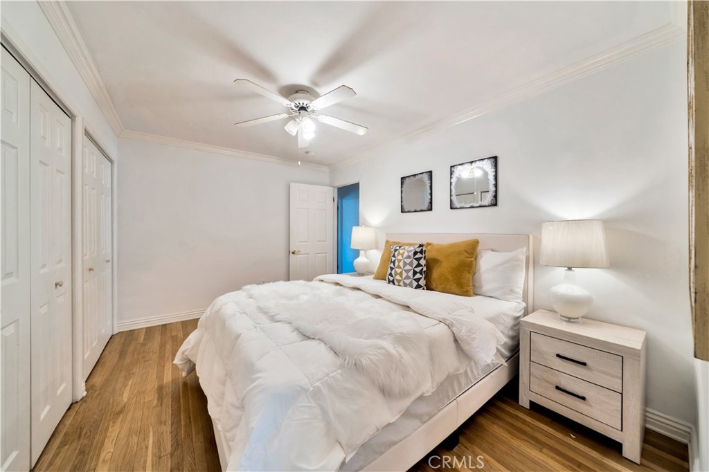 Bright Bedroom with White Bedding and Wooden Floor in Real Estate Listing