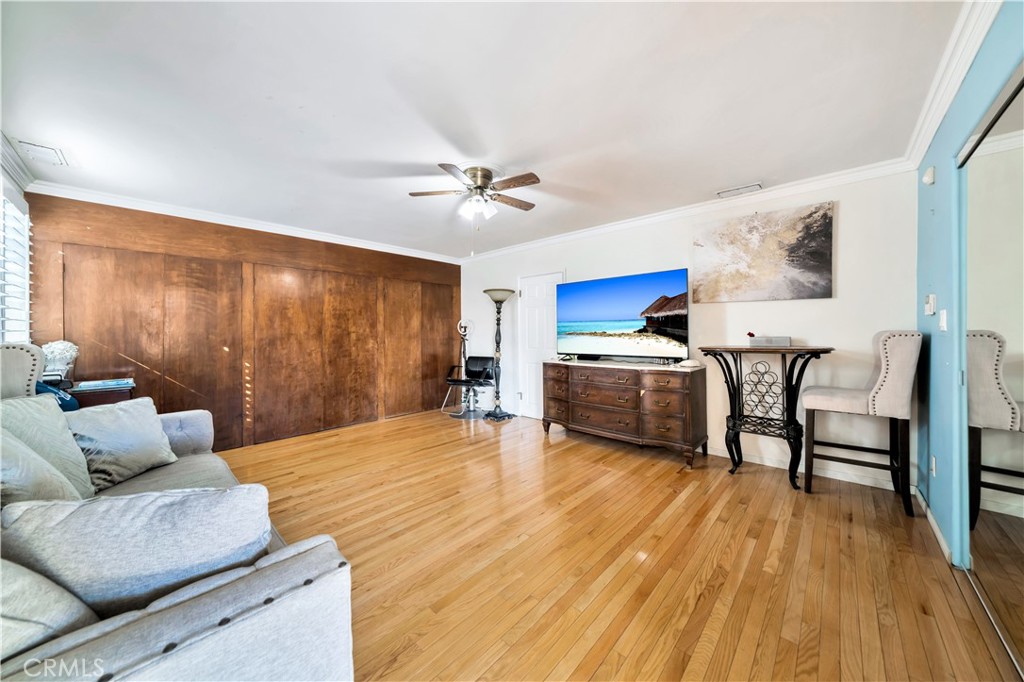 Living room with wood paneling, ceiling fan, and hardwood flooring