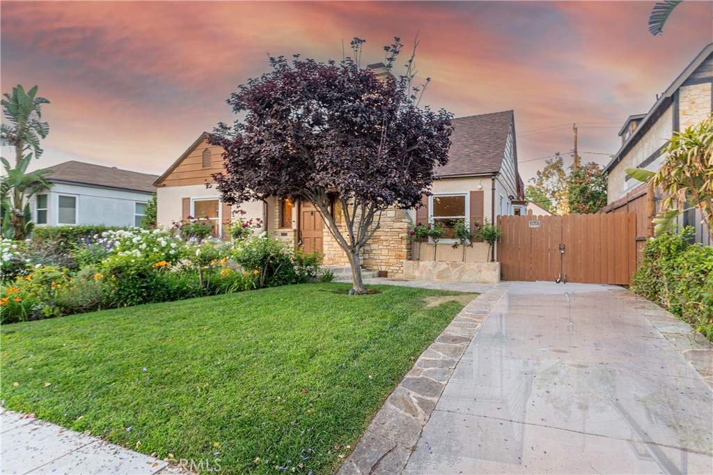 Charming Single-Story Home with Manicured Lawn and Vibrant Flower Garden