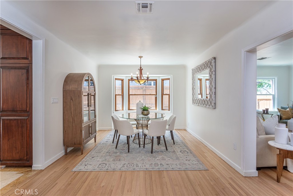 Elegant Dining Room with Glass Table, White Chairs, and Wooden Flooring