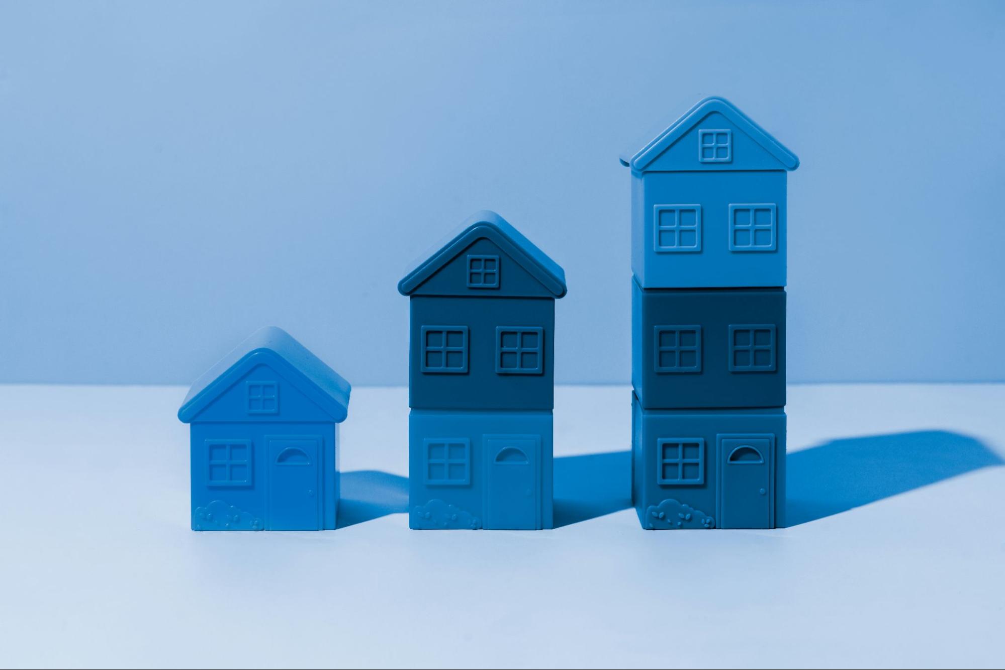 Three Blue Toy Houses in Increasing Sizes on White Surface