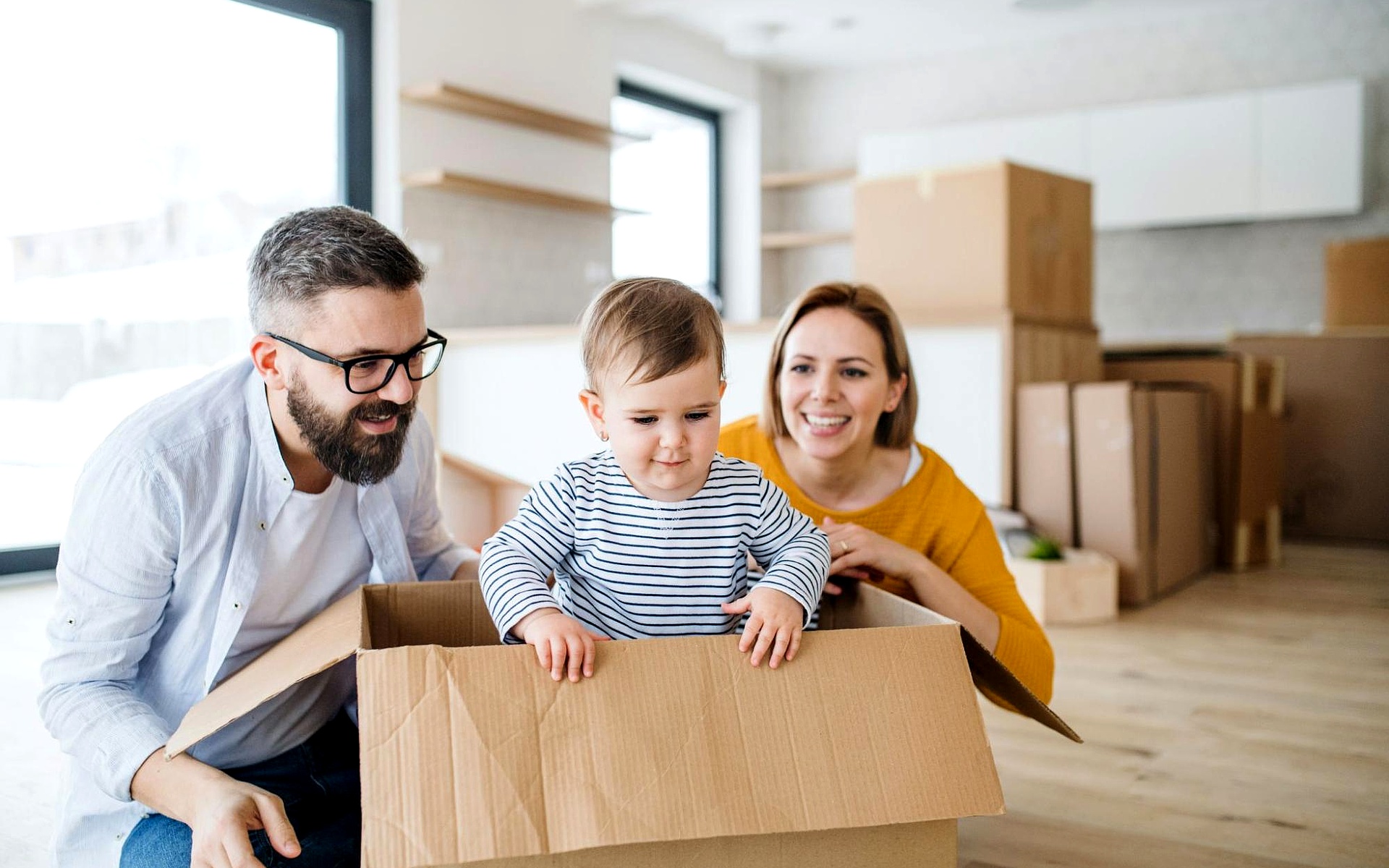 Family Unpacking Cardboard Boxes in New Home with Real Estate Agent