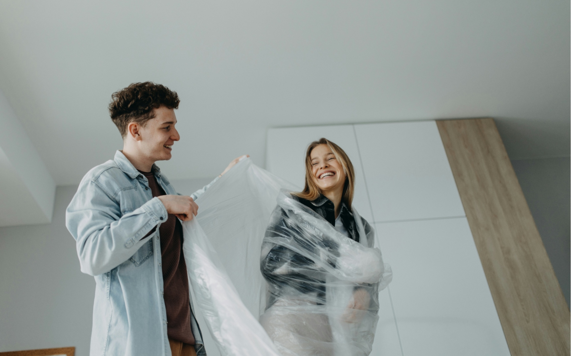 Couple Packing Items with Plastic Wrap in Modern Home