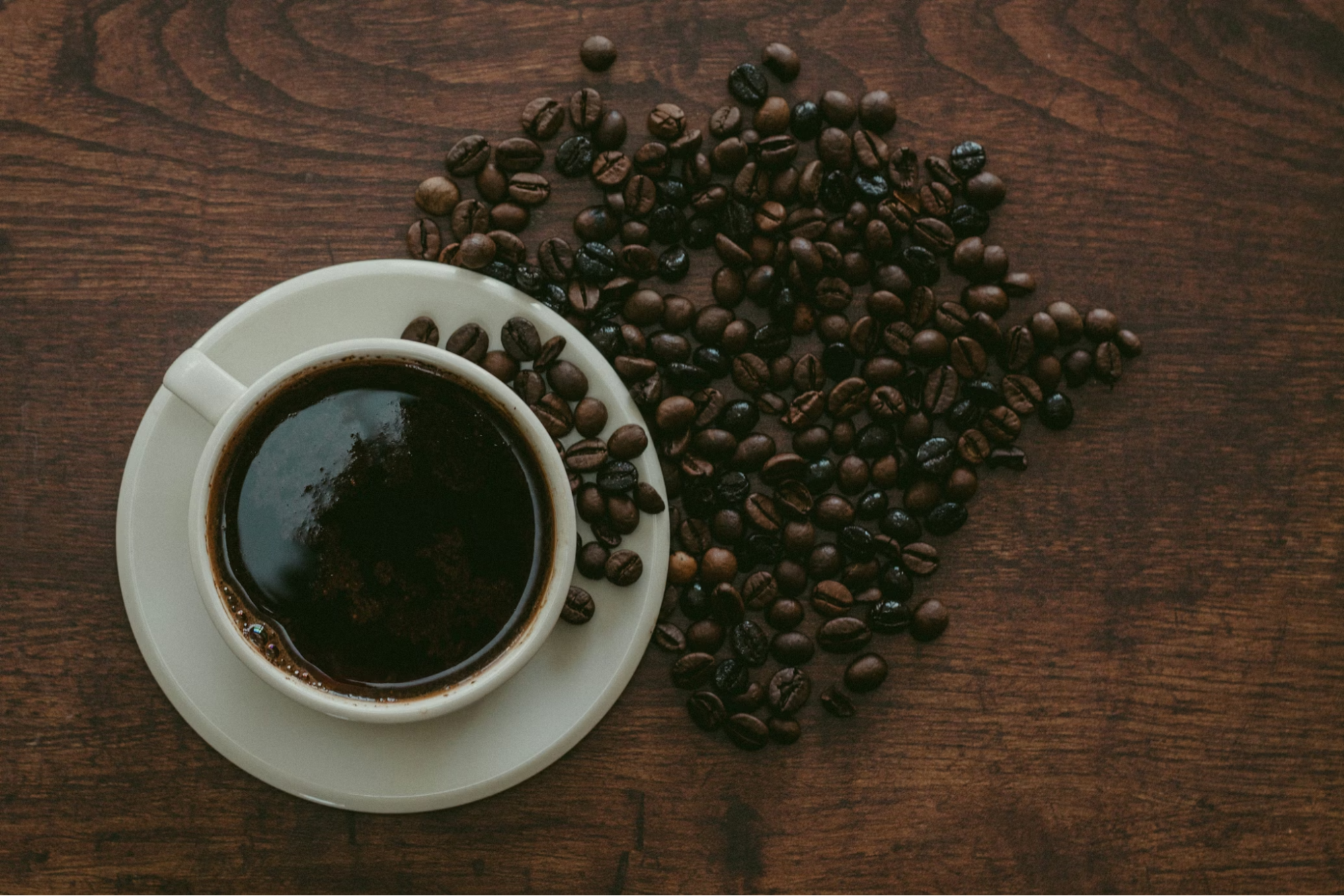 Cup of Coffee with Roasted Beans on Wooden Table